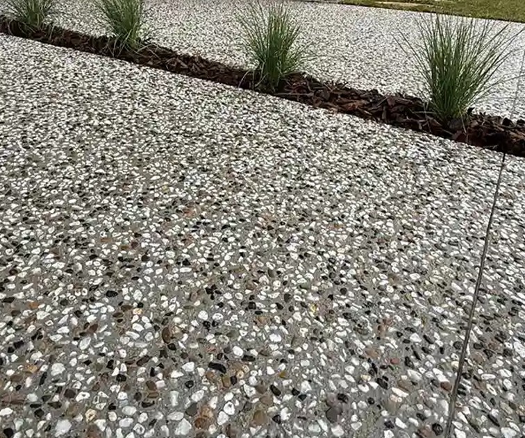 Exposed aggregate concrete edged against a bark garden strip